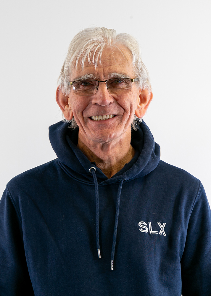 Paul Armstrong smiling warmly at the camera, wearing black glasses and standing against a clean white background.